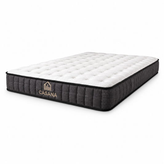 A Casana mattress shown at a three-quarter angle on a clean white background. The mattress features a white tufted top surface and a dark grey quilted side border with the gold 'CASANA' brand logo.