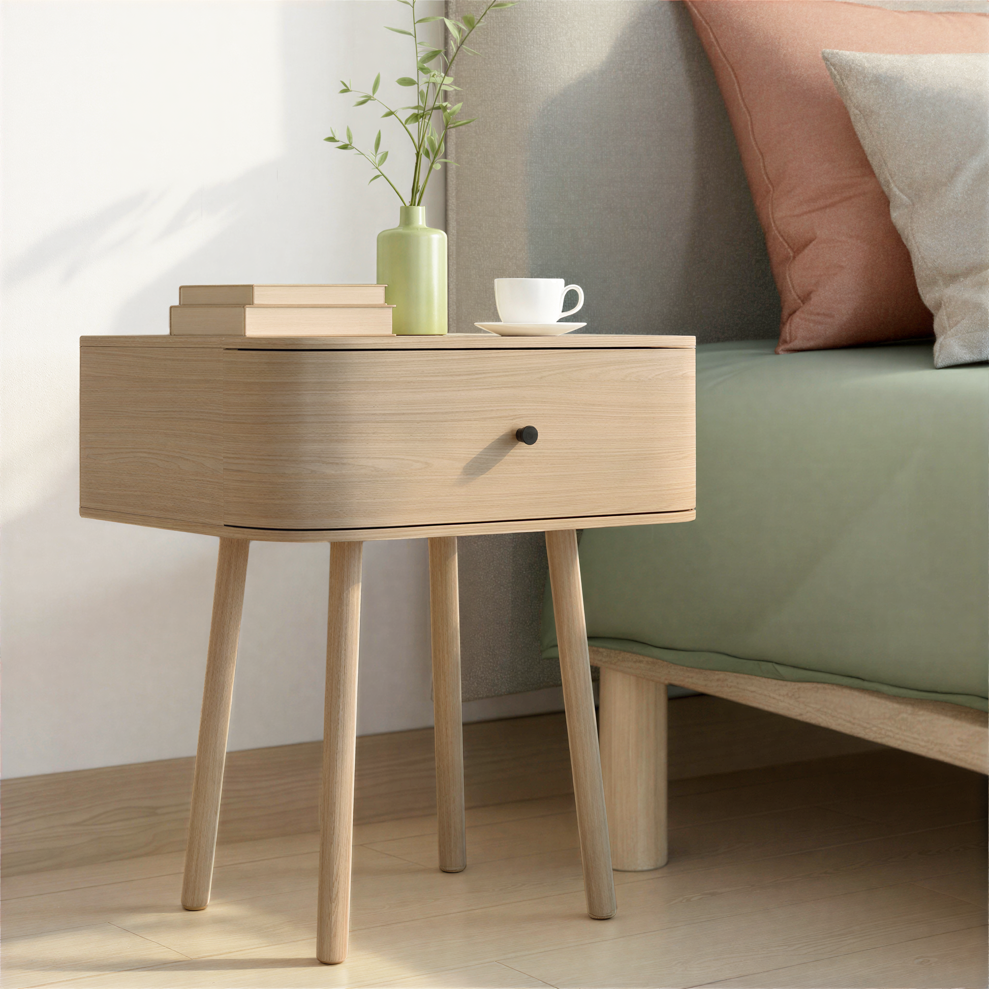 Light oak bedside table with drawer storage placed beside a bed in a softly styled bedroom.