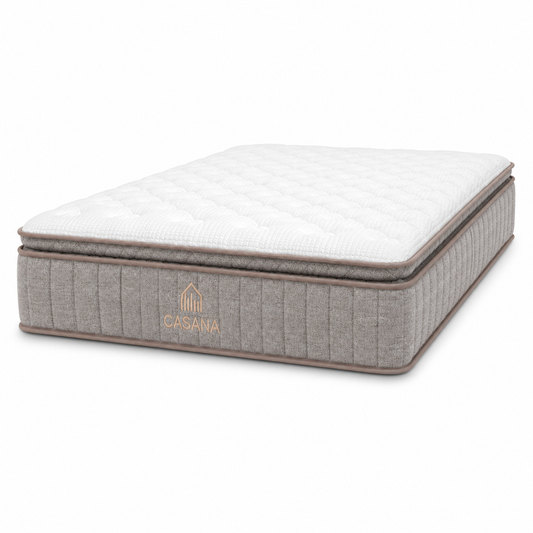 A Casana brand mattress shown at a three-quarter angle on a clean white background. The mattress features a white quilted top surface and a textured gray side panel with the brand name and logo embroidered in gold.