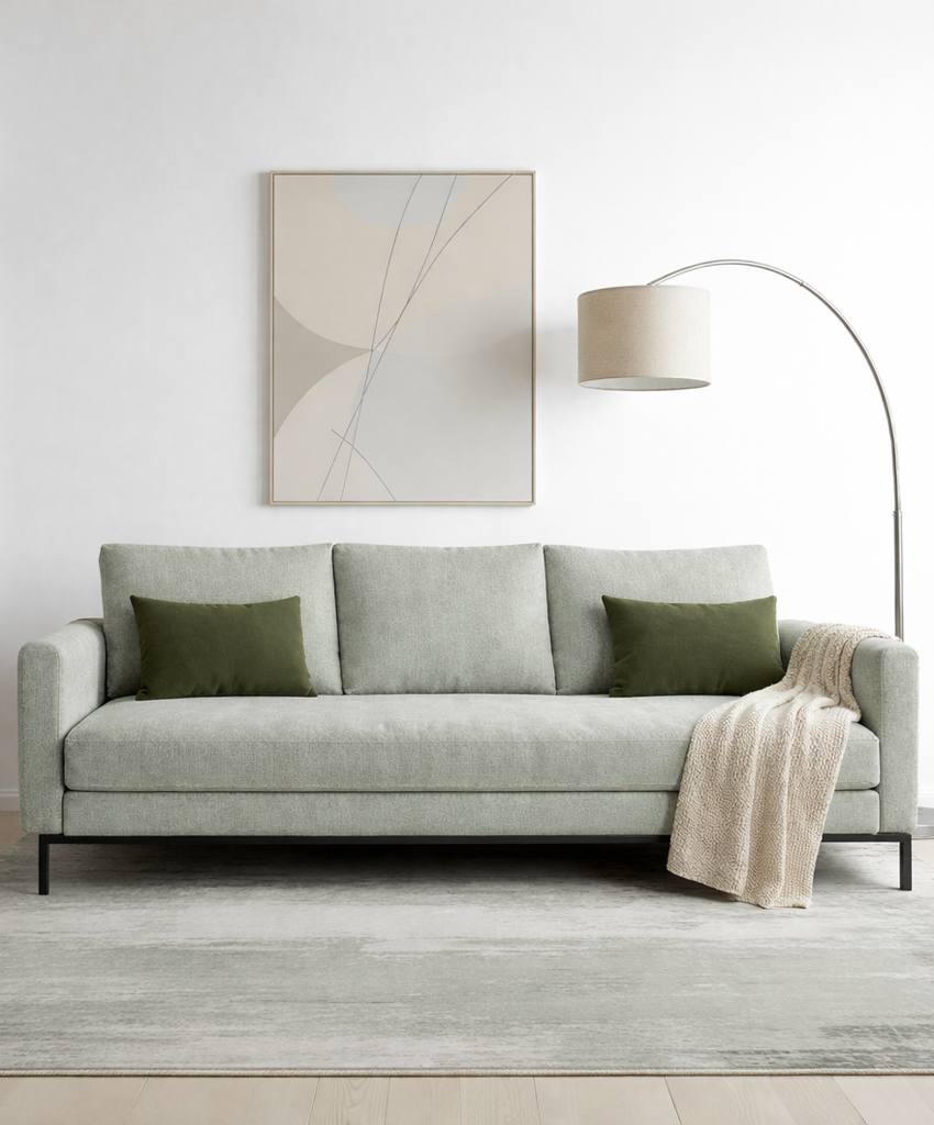 Green sofa with green cushions and a beige blanket in a modern living room.