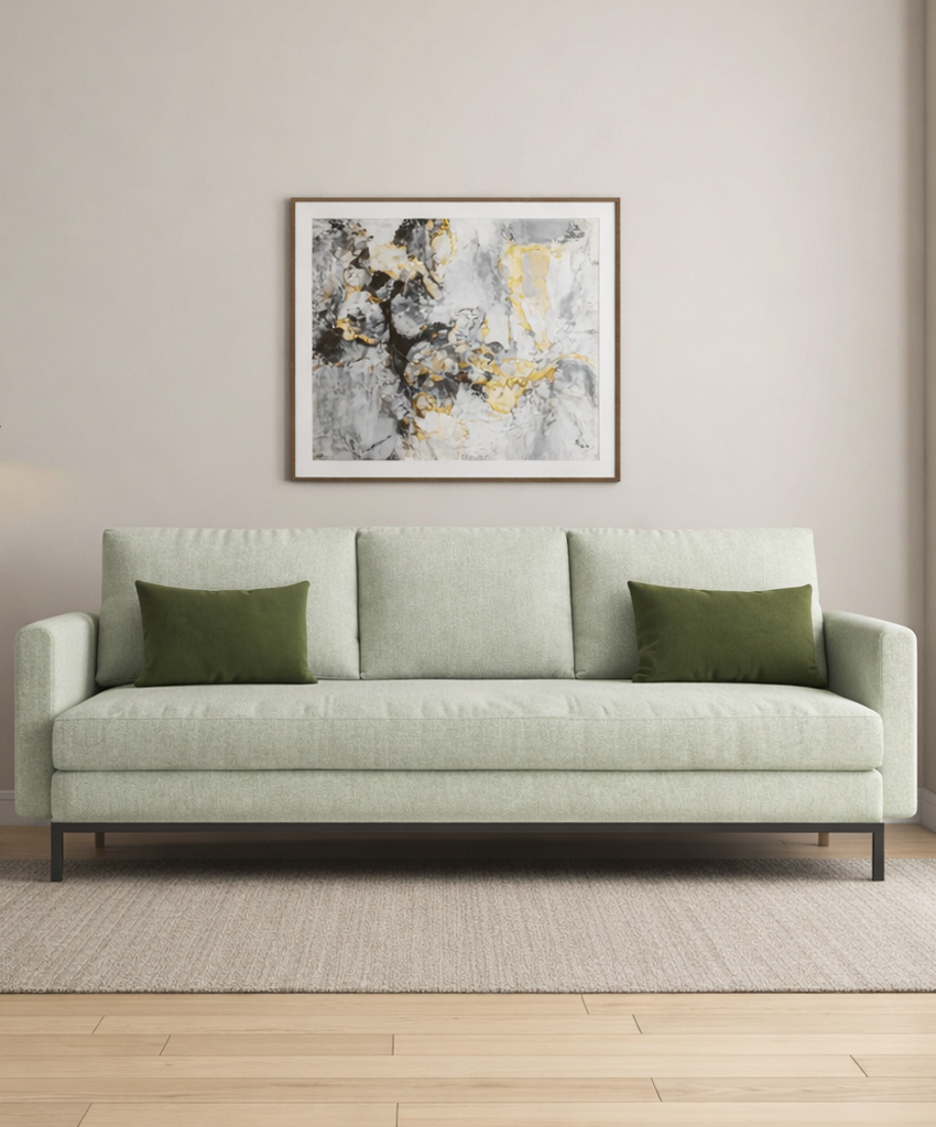 Light green sofa with green cushions in a room with a abstract painting on the wall.