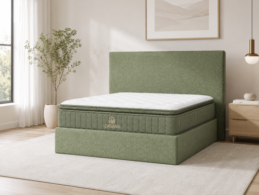 A green upholstered bed frame with a matching headboard and a white mattress, shown in a bright, modern bedroom setting with a window, plant, and bedside table.