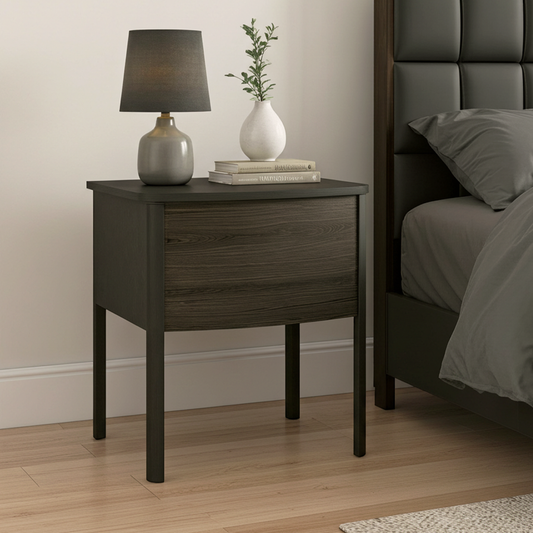 Wooden nightstand with lamp and books next to a bed in a bedroom setting