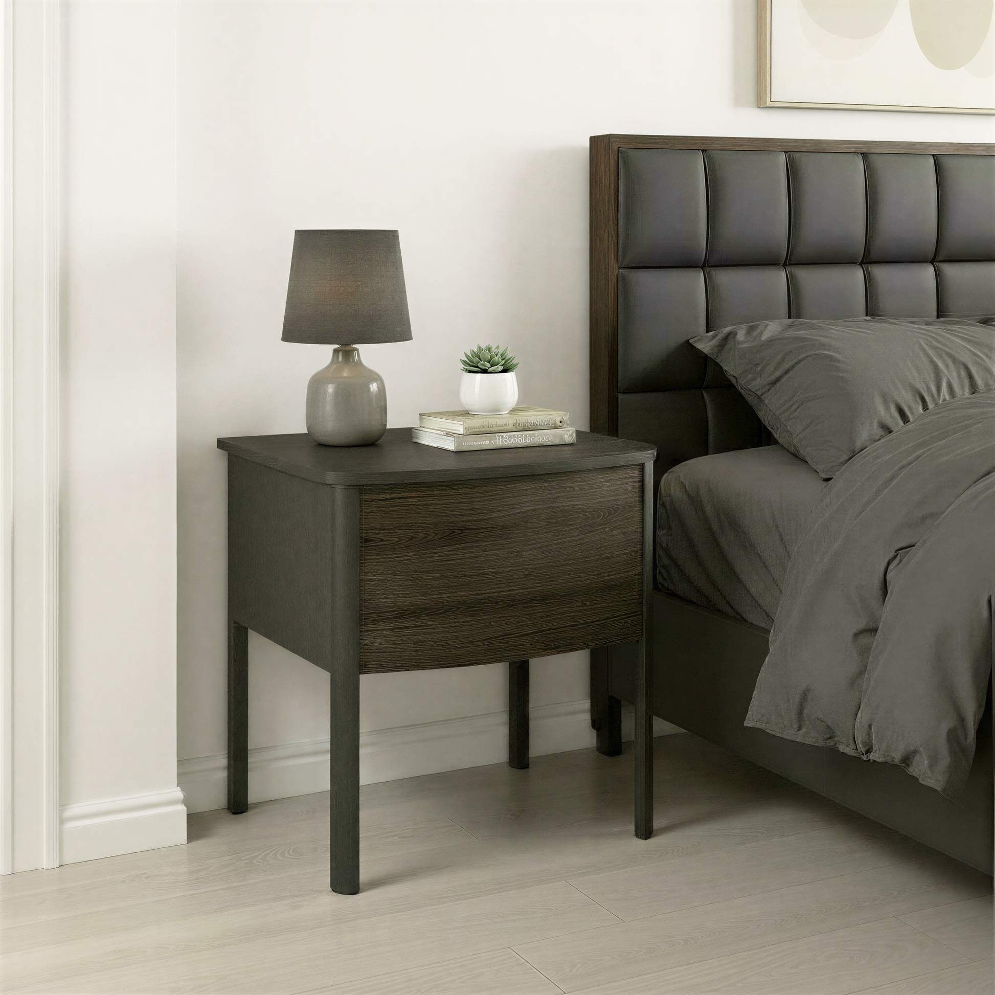 Black nightstand with wooden drawer next to a bed in a bedroom setting