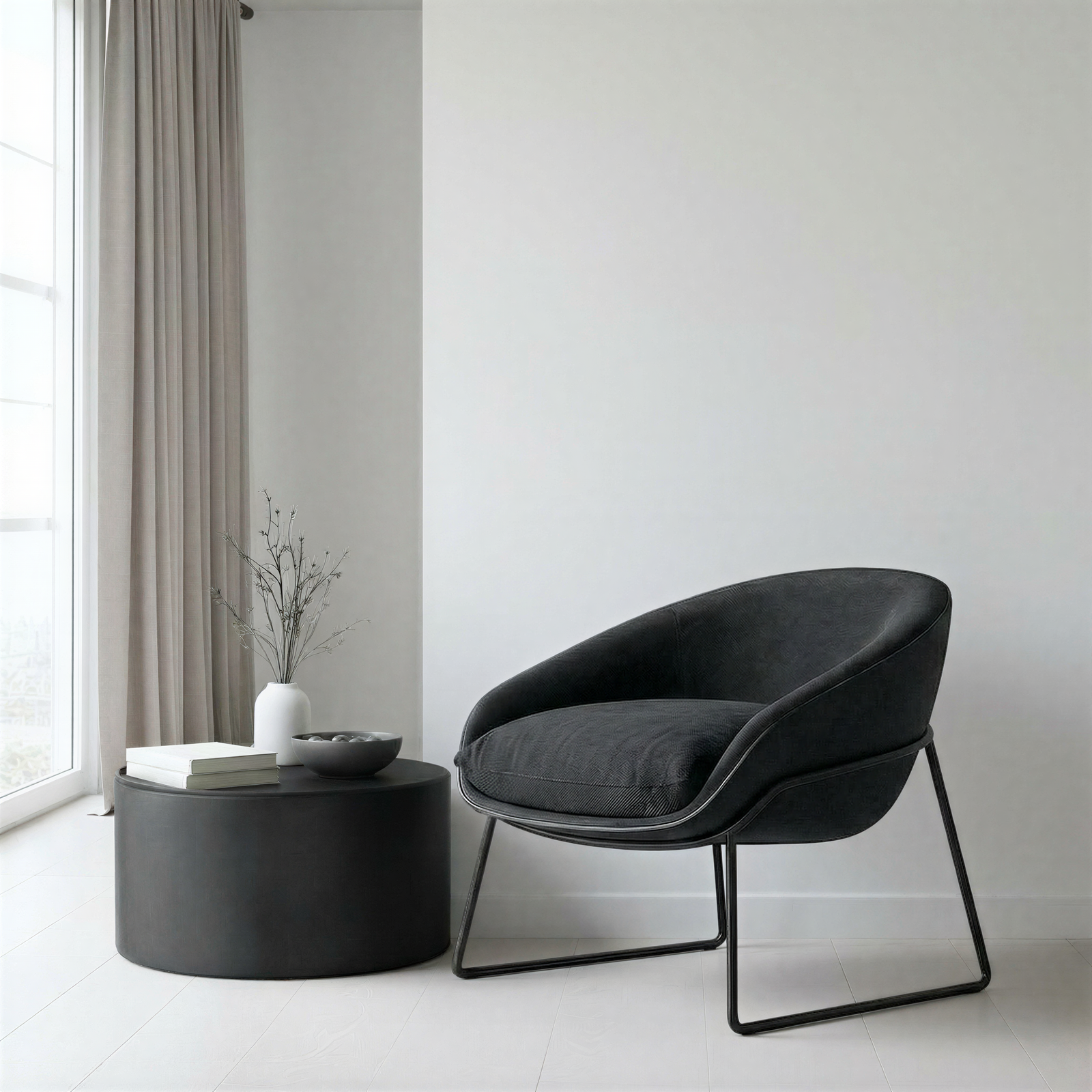 Modern black chair and round table in a minimalistic room with white walls and light grey curtains.
