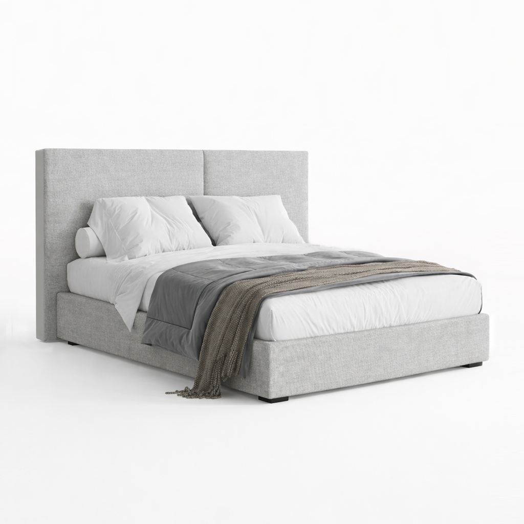 Grey upholstered bed with white bedding and a throw blanket on a white background