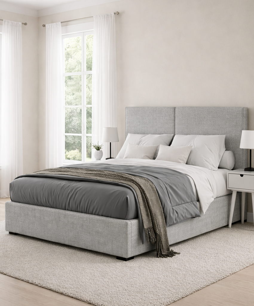 Neatly made grey double bed with grey bedding in a bright bedroom