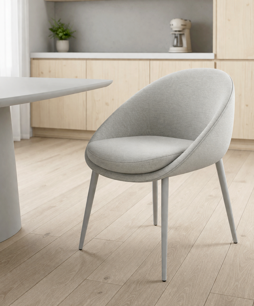 Grey dining chair in a modern kitchen setting with wooden flooring and light-colored cabinets.