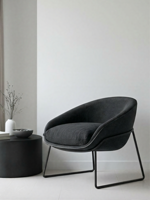 Modern black chair in a minimalistic room with a white wall and light-colored floor.