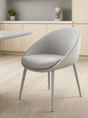 Grey dining chair in a kitchen setting with light wood cabinets and a countertop.