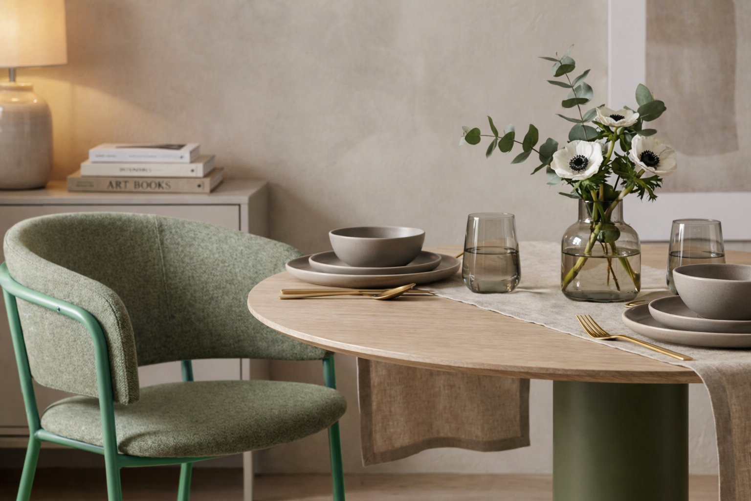 Dining room with a table set for a meal, featuring a green chair and a vase with flowers.
