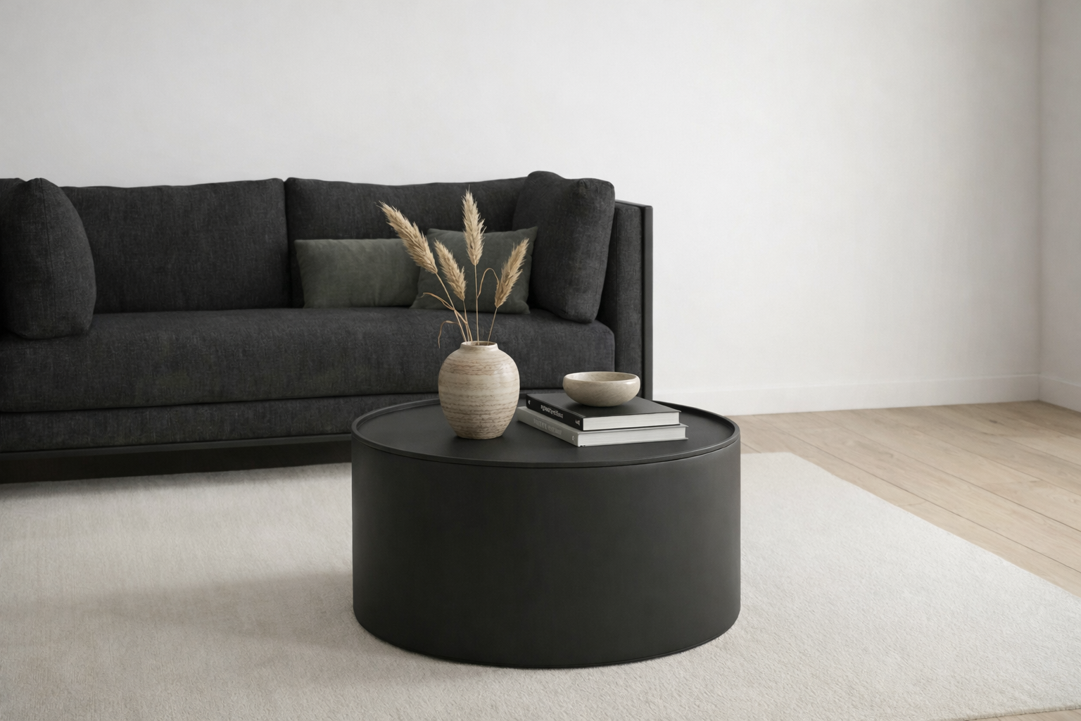 Modern living room with a black sofa and round black coffee table.