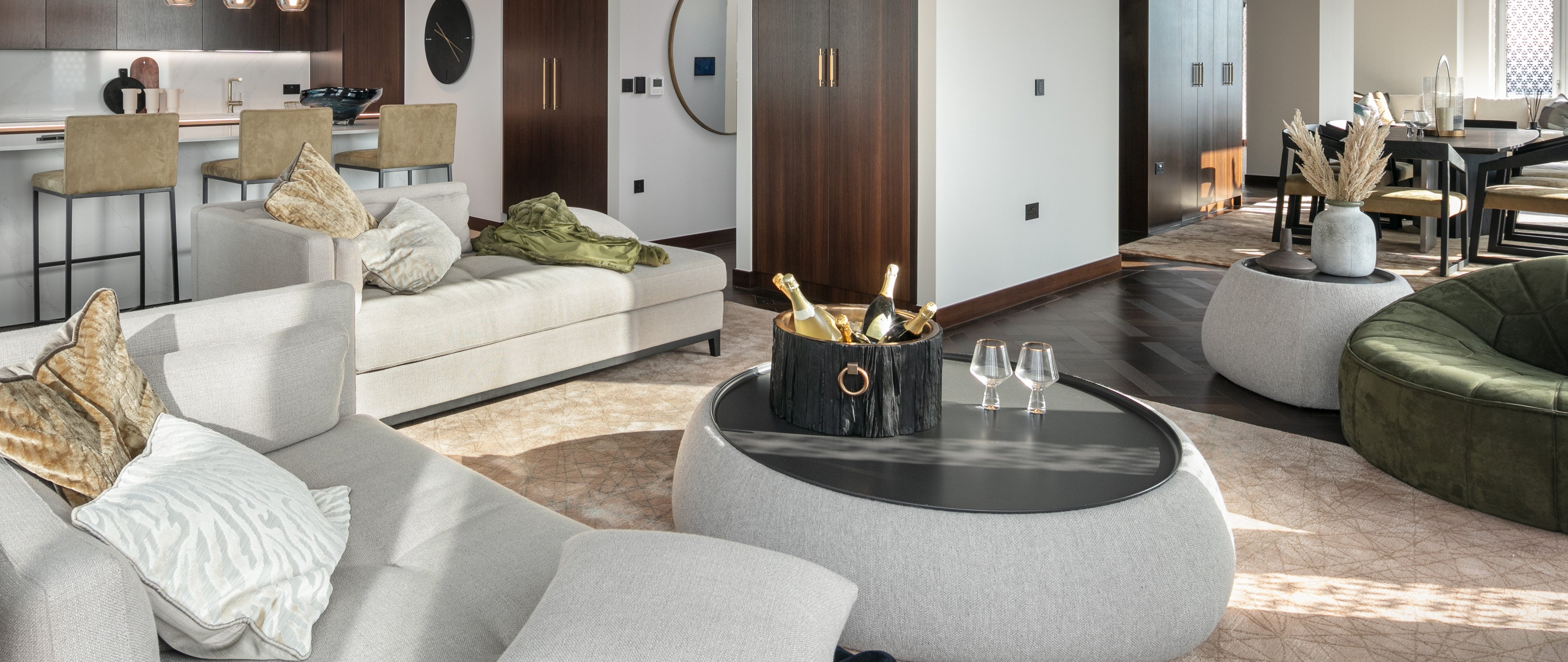 Modern living room with white and green furniture, a coffee table with wine glasses and bottles.